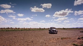 Movie still from “Walkabout” (1971), directed by Nicolas Roeg – An old car is parked in the middle of a field; Extreme Wide shot, High angle