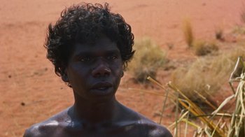 Movie still from “Walkabout” (1971), directed by Nicolas Roeg – A person with a black skin and curly black hair; Close Up shot, High angle