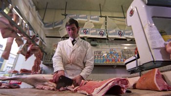 Movie still from “Walkabout” (1971), directed by Nicolas Roeg – A man in a butcher shop cutting up meat; Medium shot, Low angle