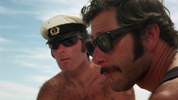 Movie still from “Walkabout” (1971), directed by Nicolas Roeg – Two men wearing hats and sunglasses on a beach; Close Up shot, Low angle