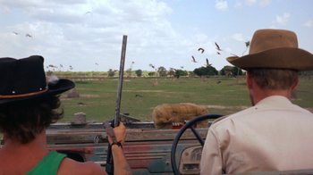 Movie still from “Walkabout” (1971), directed by Nicolas Roeg – A man holding a rifle in the back of a truck; Wide shot, Over the shoulder angle