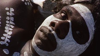 Movie still from “Walkabout” (1971), directed by Nicolas Roeg – A person with a white face painted on it; Extreme Close Up shot, High angle