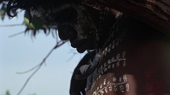 Movie still from “Walkabout” (1971), directed by Nicolas Roeg – A man with a face paint and a feather in his ear; Extreme Close Up shot, Low angle