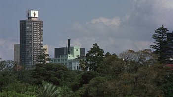 Movie still from “Walkabout” (1971), directed by Nicolas Roeg – A view of some buildings and trees in the distance; Extreme Wide shot, Low angle