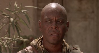 Movie still from “Walker” (1987), directed by Alex Cox – A man with a bald head is looking at the camera; Close Up shot, Low angle