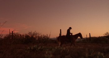 Movie still from “Walker” (1987), directed by Alex Cox – A man riding a horse in a field at sunset; Extreme Wide shot, Low angle