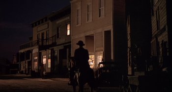 Movie still from “Walker” (1987), directed by Alex Cox – A man riding a horse down a street at night; Extreme Wide shot, Low angle