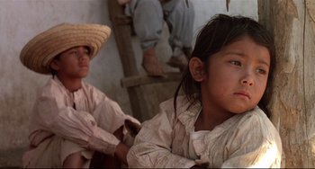 Movie still from “Walker” (1987), directed by Alex Cox – Two young children sitting on a bench in front of a building; Close Up shot, Low angle