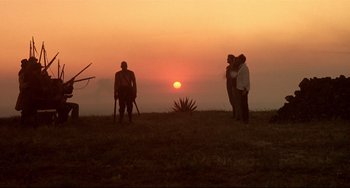 Movie still from “Walker” (1987), directed by Alex Cox – A group of people standing on top of a grass covered field; Extreme Wide shot, Low angle