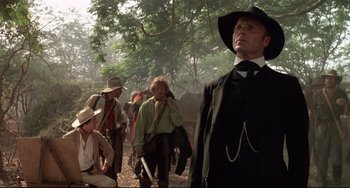 Movie still from “Walker” (1987), directed by Alex Cox – A group of people in a field with trees in the background; Medium shot, Low angle