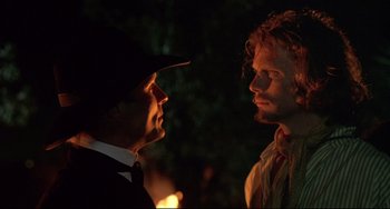 Movie still from “Walker” (1987), directed by Alex Cox – A man and a woman are talking in the dark; Close Up shot, Over the shoulder angle