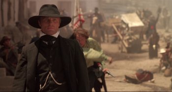 Movie still from “Walker” (1987), directed by Alex Cox – A man in a hat is standing in front of another man in a hat; Medium shot, Low angle