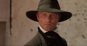 Movie still from “Walker” (1987), directed by Alex Cox – A person wearing a hat and a suit; Close Up shot, Low angle