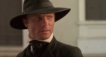 Movie still from “Walker” (1987), directed by Alex Cox – A person wearing a hat and a suit; Close Up shot, Low angle