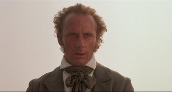 Movie still from “Walker” (1987), directed by Alex Cox – A person wearing a suit and tie; Close Up shot, Low angle