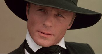 Movie still from “Walker” (1987), directed by Alex Cox – A person wearing a suit and hat; Close Up shot, Low angle
