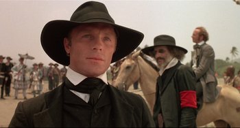 Movie still from “Walker” (1987), directed by Alex Cox – A man wearing a hat and a tie; Close Up shot, Low angle