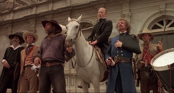 Movie still from “Walker” (1987), directed by Alex Cox – A group of men standing next to each other on a white horse; Wide shot, Low angle
