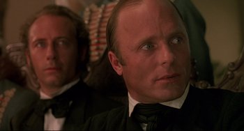 Movie still from “Walker” (1987), directed by Alex Cox – A man in a suit and tie looking at the camera; Close Up shot, Over the shoulder angle