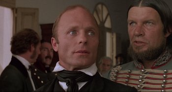 Movie still from “Walker” (1987), directed by Alex Cox – A person wearing a suit and tie; Close Up shot, Low angle