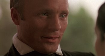 Movie still from “Walker” (1987), directed by Alex Cox – A person wearing a suit and tie; Close Up shot, Over the shoulder angle