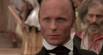 Movie still from “Walker” (1987), directed by Alex Cox – A person wearing a suit and tie; Close Up shot, Low angle