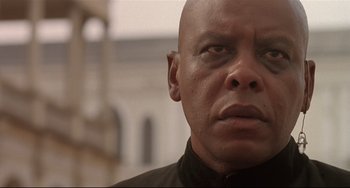 Movie still from “Walker” (1987), directed by Alex Cox – A bald man in a black shirt looking into the distance; Close Up shot, Low angle