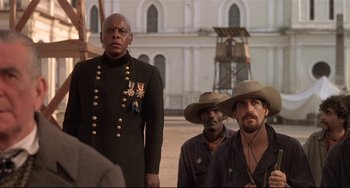 Movie still from “Walker” (1987), directed by Alex Cox – A group of men standing next to each other on a street; Medium shot, Low angle