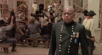 Movie still from “Walker” (1987), directed by Alex Cox – A man in a military uniform standing in front of a group of people; Medium shot, Low angle