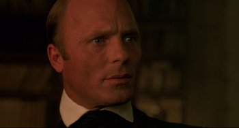 Movie still from “Walker” (1987), directed by Alex Cox – A person wearing a suit and tie; Close Up shot, Over the shoulder angle