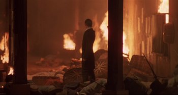 Movie still from “Walker” (1987), directed by Alex Cox – A man standing in a burning pile of garbage; Wide shot, High angle