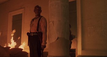 Movie still from “Walker” (1987), directed by Alex Cox – A man standing next to a pillar in a room; Medium shot, Low angle