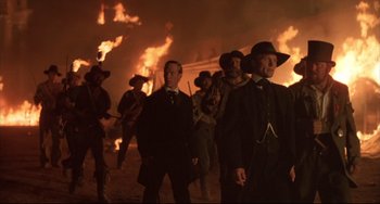 Movie still from “Walker” (1987), directed by Alex Cox – A group of men standing next to each other in front of fire; Medium shot, Low angle
