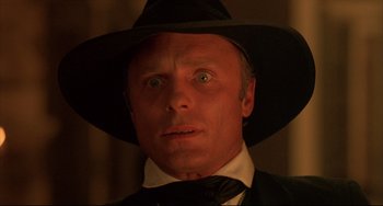 Movie still from “Walker” (1987), directed by Alex Cox – A person wearing a suit and a hat; Close Up shot, Low angle