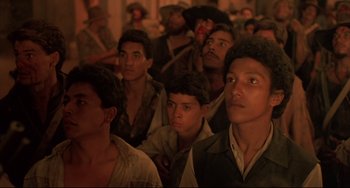 Movie still from “Walker” (1987), directed by Alex Cox – A group of men standing next to each other in a room; Close Up shot, High angle