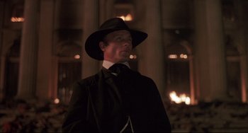 Movie still from “Walker” (1987), directed by Alex Cox – A man wearing a hat and a suit smoking a cigarette; Close Up shot, Low angle