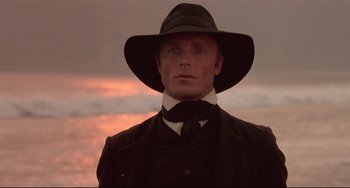 Movie still from “Walker” (1987), directed by Alex Cox – A man wearing a black hat and a black suit; Close Up shot, Low angle