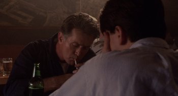 Movie still from “Wall Street” (1987), directed by Oliver Stone – A man smoking a cigarette while another man looks on; Close Up shot, Over the shoulder angle