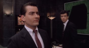 Movie still from “Wall Street” (1987), directed by Oliver Stone – A man in a suit standing next to another man in a suit; Close Up shot, Over the shoulder angle