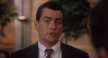 Movie still from “Wall Street” (1987), directed by Oliver Stone – A person wearing a suit and tie; Close Up shot, Over the shoulder angle