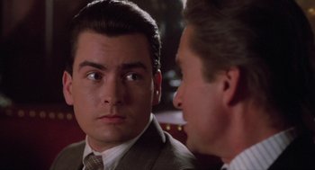 Movie still from “Wall Street” (1987), directed by Oliver Stone – A man in a suit and tie looking at another man in a suit and tie; Close Up shot, Over the shoulder angle