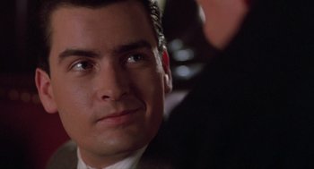Movie still from “Wall Street” (1987), directed by Oliver Stone – A man in a suit and tie looking to his left; Close Up shot, Over the shoulder angle