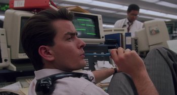 Movie still from “Wall Street” (1987), directed by Oliver Stone – A man sitting in front of computer monitors; Close Up shot, Low angle