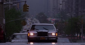Movie still from “Wall Street” (1987), directed by Oliver Stone – A car driving down the street in the rain; Wide shot, Low angle