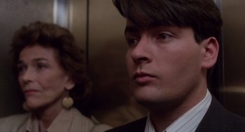 Movie still from “Wall Street” (1987), directed by Oliver Stone – A person wearing a suit and tie; Close Up shot, Over the shoulder angle