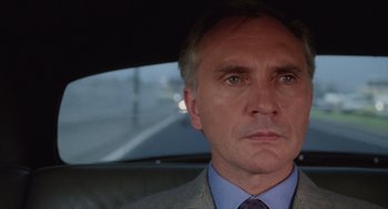 Movie still from “Wall Street” (1987), directed by Oliver Stone – A person wearing a suit in a car; Close Up shot, Low angle