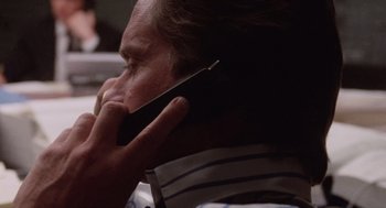 Movie still from “Wall Street” (1987), directed by Oliver Stone – A person talking on a cell phone; Close Up shot, Low angle