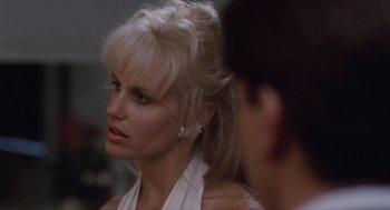 Movie still from “Wall Street” (1987), directed by Oliver Stone – A woman in a white shirt is looking to her left; Close Up shot, Over the shoulder angle