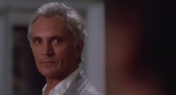 Movie still from “Wall Street” (1987), directed by Oliver Stone – A person wearing a suit and tie; Close Up shot, Over the shoulder angle