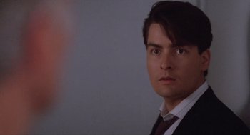 Movie still from “Wall Street” (1987), directed by Oliver Stone – A person wearing a suit and tie; Close Up shot, Over the shoulder angle